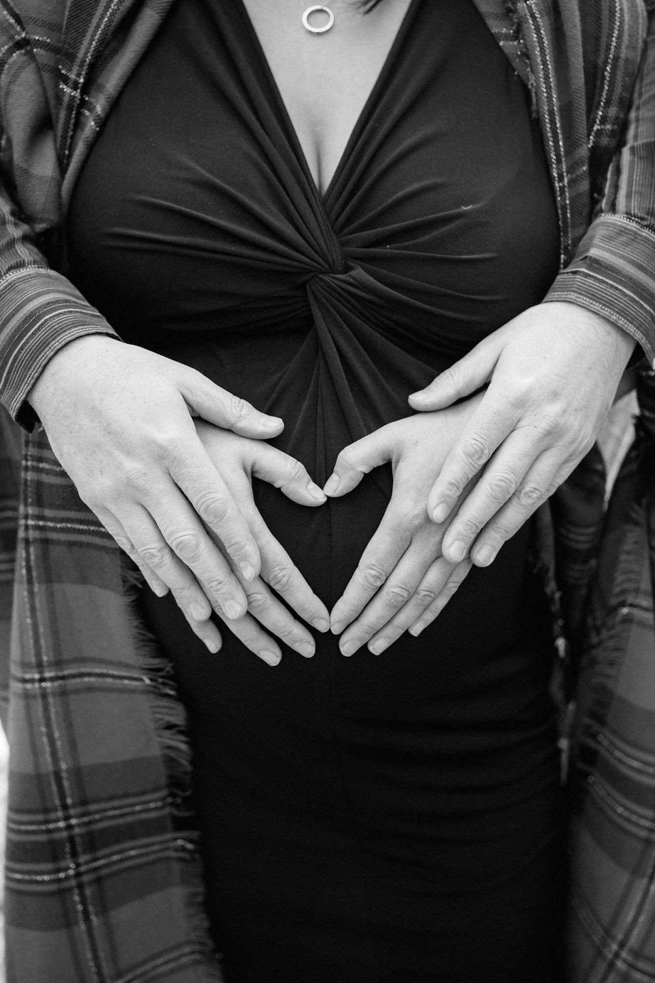Andy & Erin make a heart shape with their hands during their maternity photoshoot with Jennifer Blaak Photography.