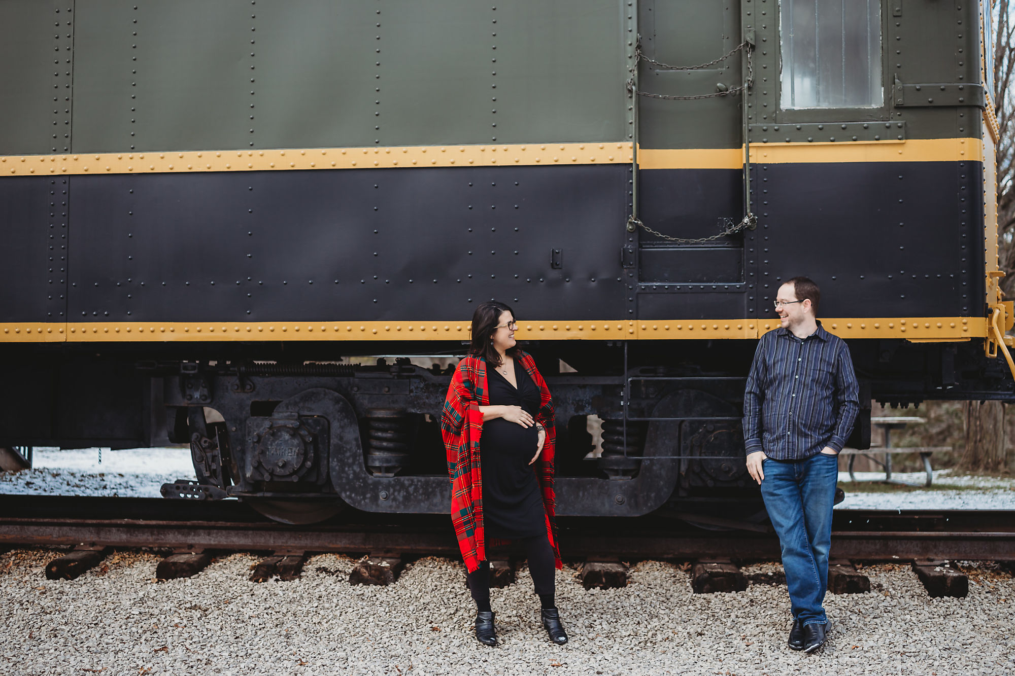 Andy & Erin pose in front of a museum train at Dundas Conservation Area in Hamilton Ontario during their maternity photoshoot with Dundas Maternity Photographer Jennifer Blaak.