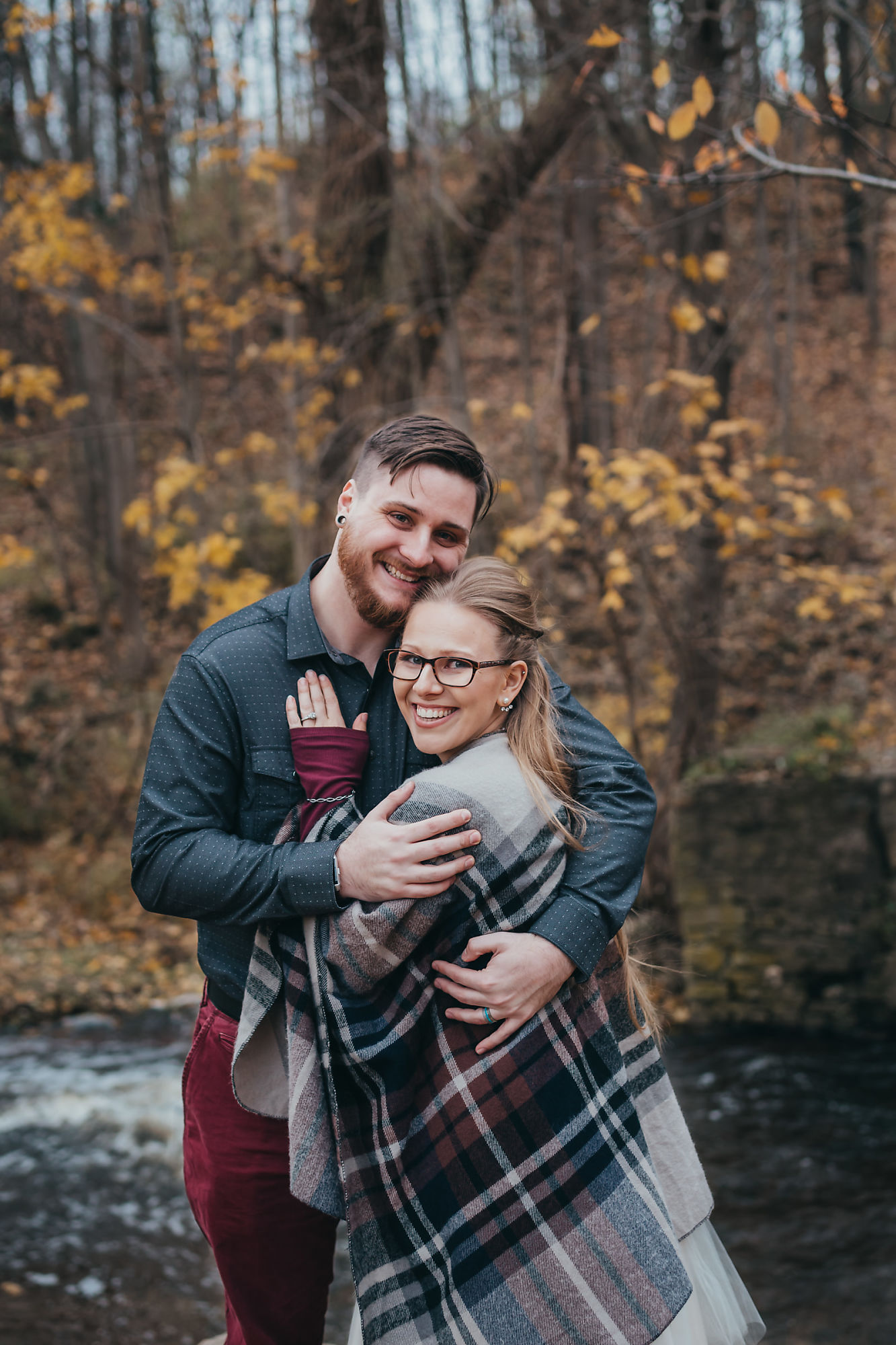 Dan and Nina pose along the shore of Smokey Hollow Falls during their fall engagement session with Dundas engagement photographer Jennifer Blaak.