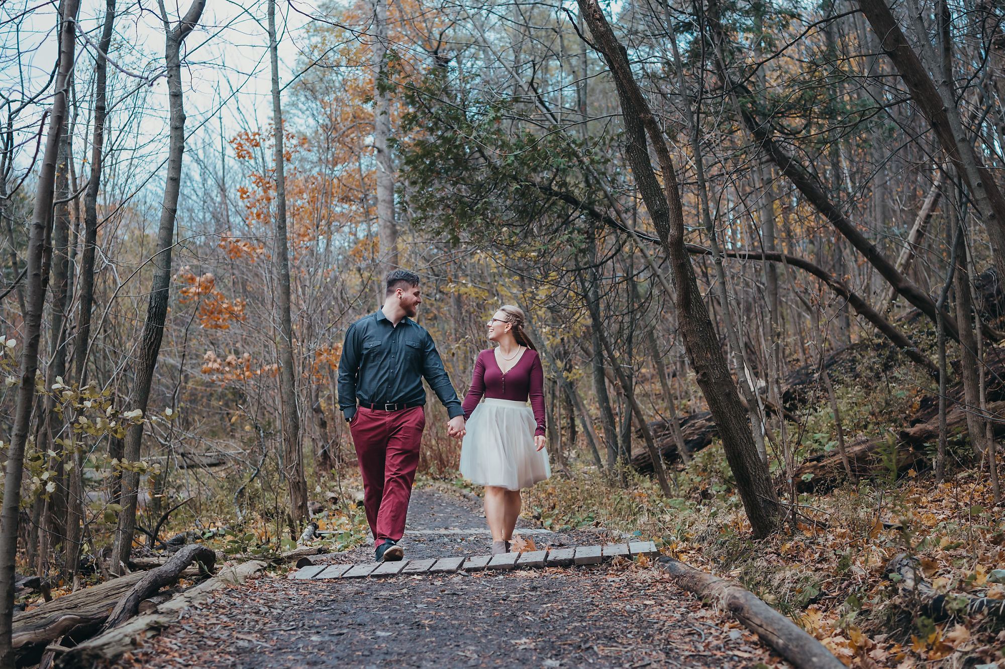 Dan and Nina holding hands during a walk in the forest near Smokey Hollow Falls during their engagement session with Dundas engagement photographer Jennifer Blaak.