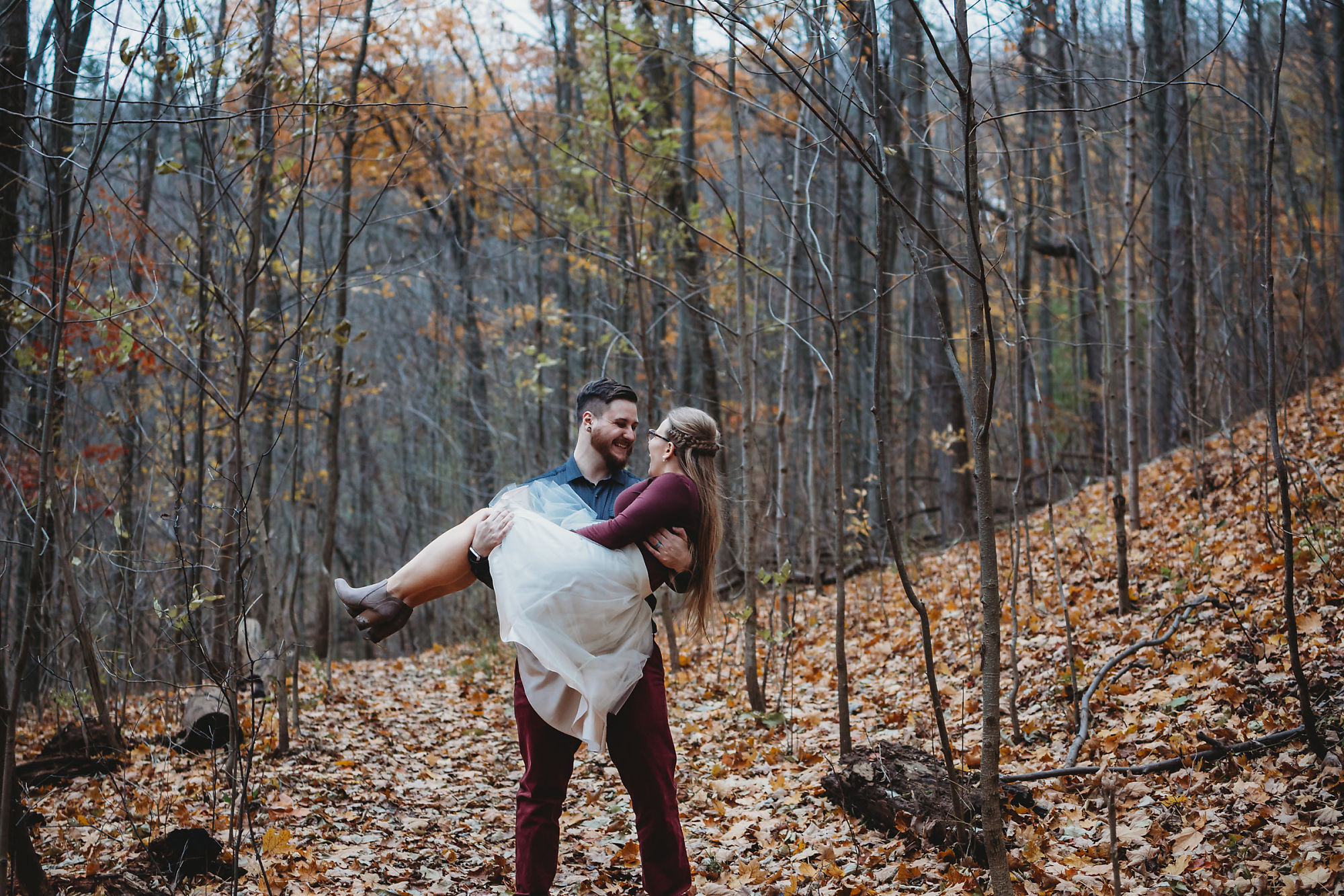 Dan sweeps Nina of her feet in a romantic embrace in the forest near Smokey Hollow Falls during their engagement session with Dundas engagement photographer Jennifer Blaak.