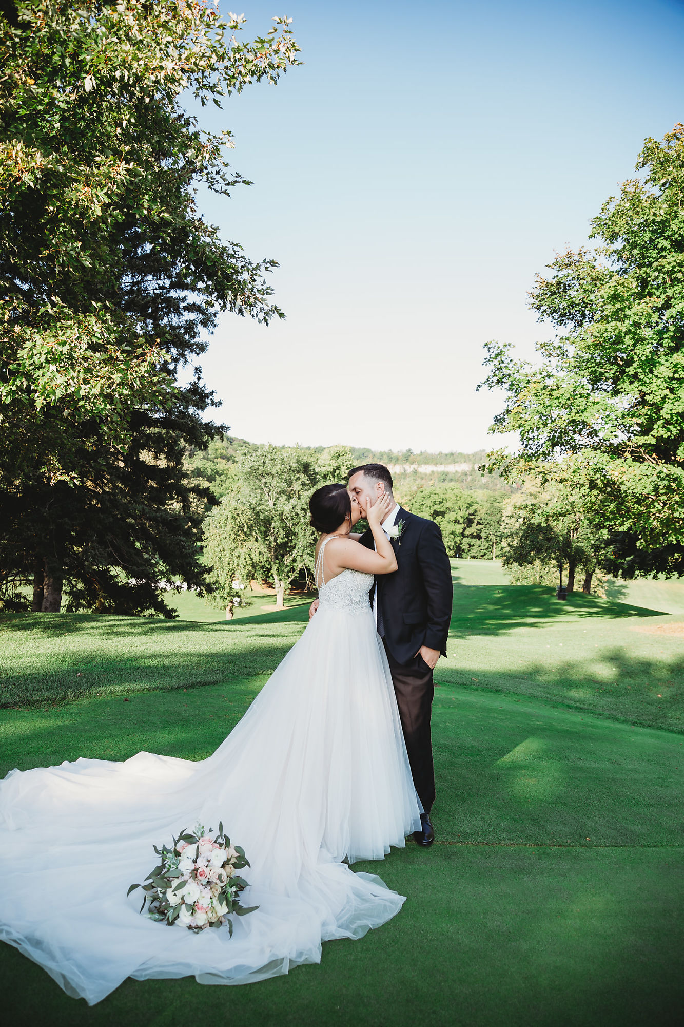A portrait of the bride and groom kissing on the green at Dundas Golf and Curling Club in Hamilton, Ontario.