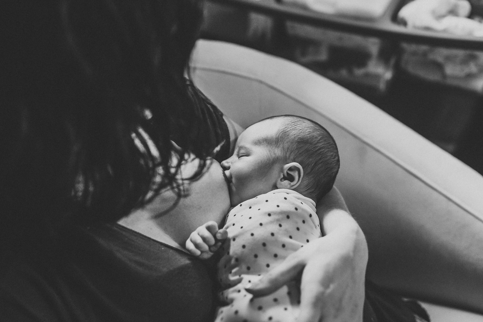 Documentary-style Dundas Newborn Photographer Jennifer Blaak captures a gentle moment between mother and baby as she breastfeeds at home during their newborn and family lifestyle photography session in Hamilton.