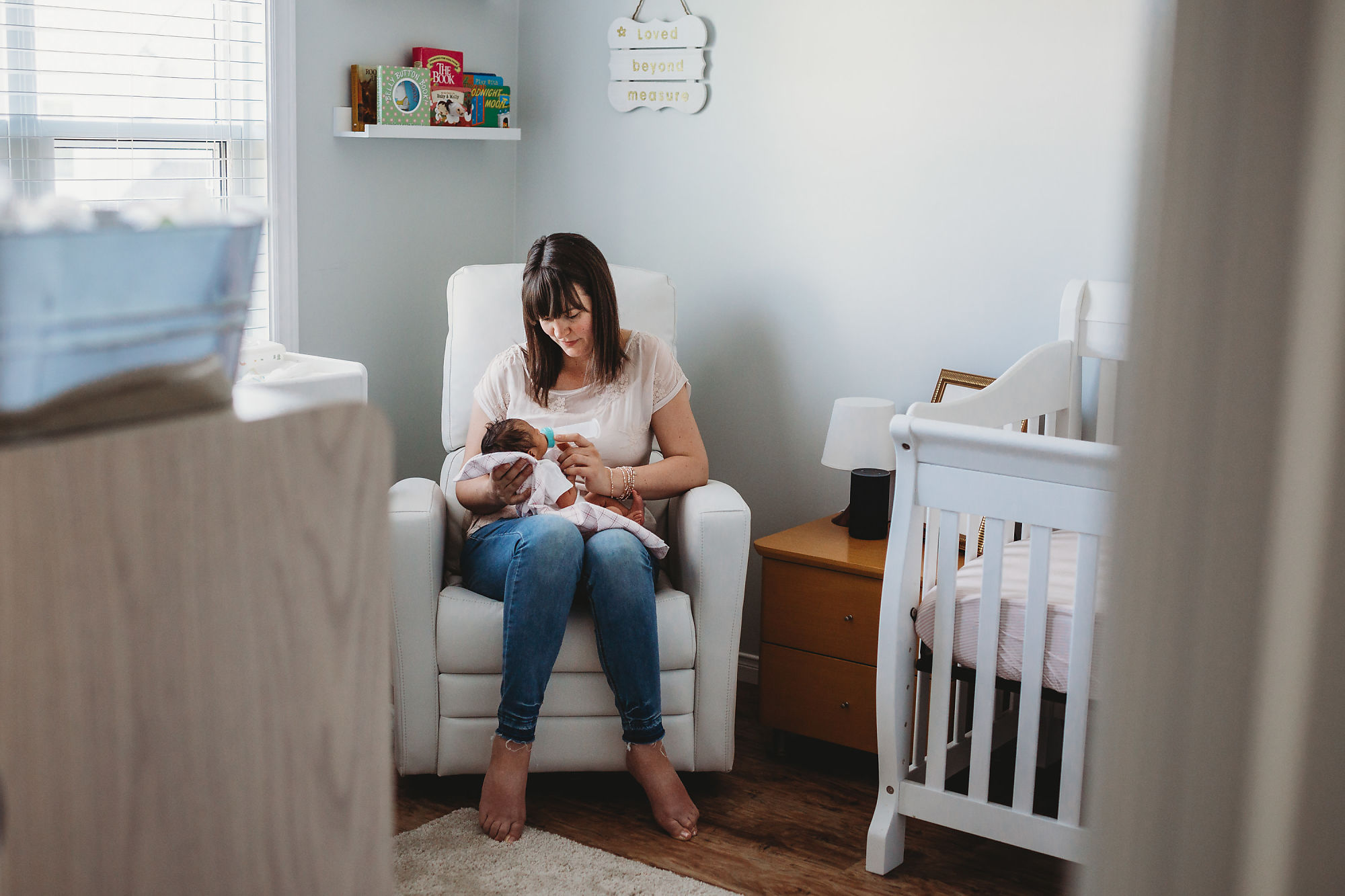 Mom feeds baby in the nursery during their lifestyle newborn photography session with Guelph Newborn Photographer Jennifer Blaak.