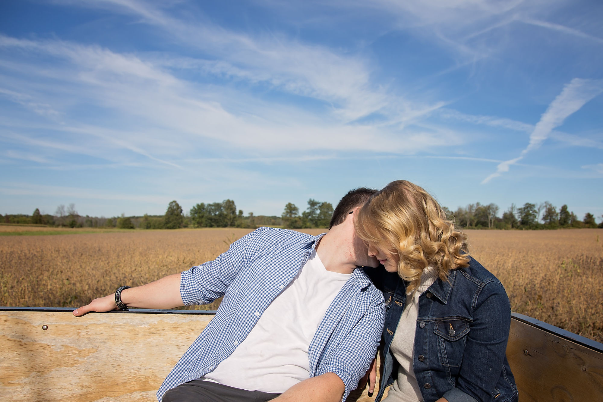 Couple Kaitlyn and Nick kiss in a wagon ride on the farm during their engagement shoot with Waterdown Engagement Photographer Jennifer Blaak.