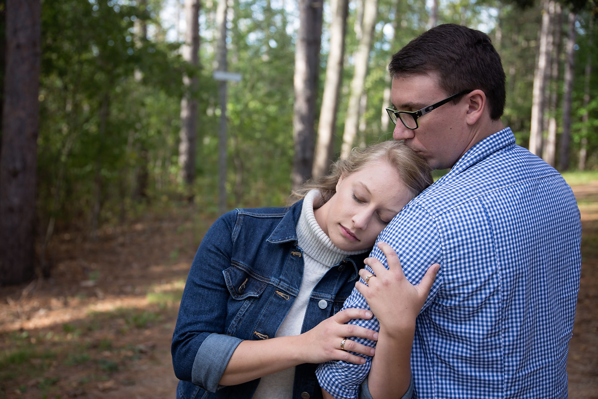 Nick kisses his fiance gently on the head as they embrace in the forest during their engagement shoot with Waterdown Engagement Photographer Jennifer Blaak.