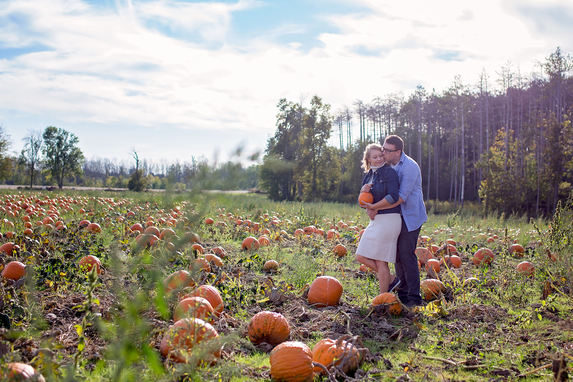 Couple Kaitlyn and Nick embrace in the pumpkin patch during their engagement shoot with Waterdown Engagement Photographer Jennifer Blaak.
